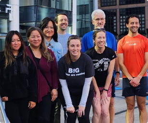 Five female and three male FHLBank Boston employees standing wearing workout clothing standing outdoors next to each other