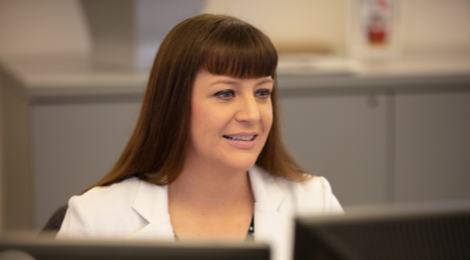 Female FHLBank Boston employee seated and facing computer screens.