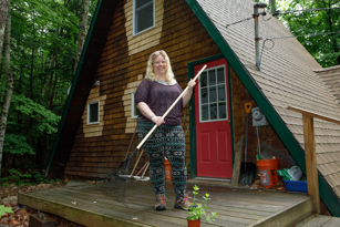 woman holding a rake standing in front of her home