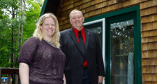 woman and man standing with home in background