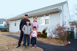 father, mother, and son and daughter outside with home in background