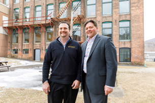 two men standing in front of an old mill building that was redeveloped