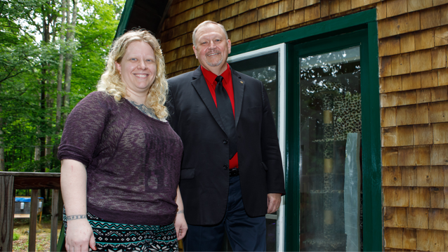 woman and man standing with home in background