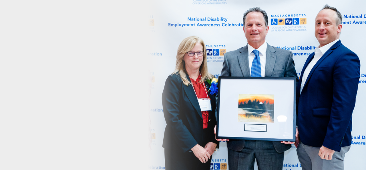 male FHLBank Boston employee holding a framed award while standing between a man and woman