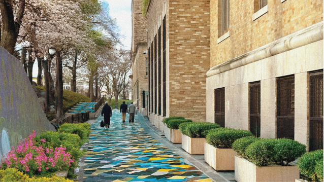 exterior of apartment building with colorful landscaping and 3 adults walking down a walkway
