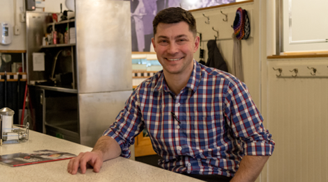 man smiling as he sits at restaurant counter
