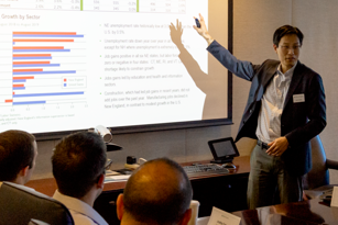 man standing in front of a screen presenting to a group of professionals
