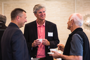 three men standing next to each and talking