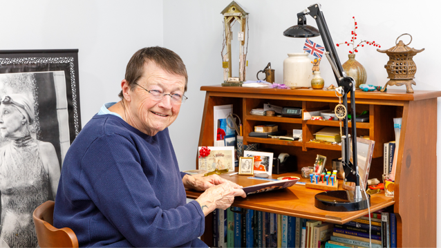 senior female smiling while sitting at desk and holding a folder