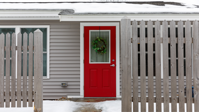 Maine senor housing unit with red door adorned with a wreath and snow on the ground