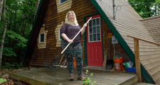 woman holding a rake standing in front of her home