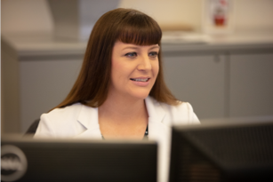 Female FHLBank Boston employee seated and facing computer screens.