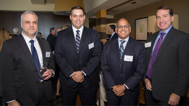 four smiling men in suits and ties standing next to each other