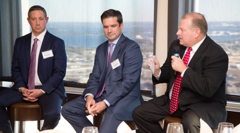 three male members seated as part of a panel speaking at an insurance company meeting
