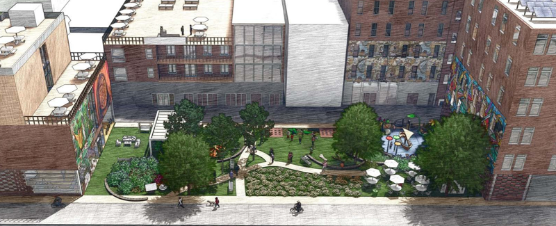 Overhead shot of a series of multi-level buildings with a greenspace with trees, walkways, a playground, and people walking in the middle