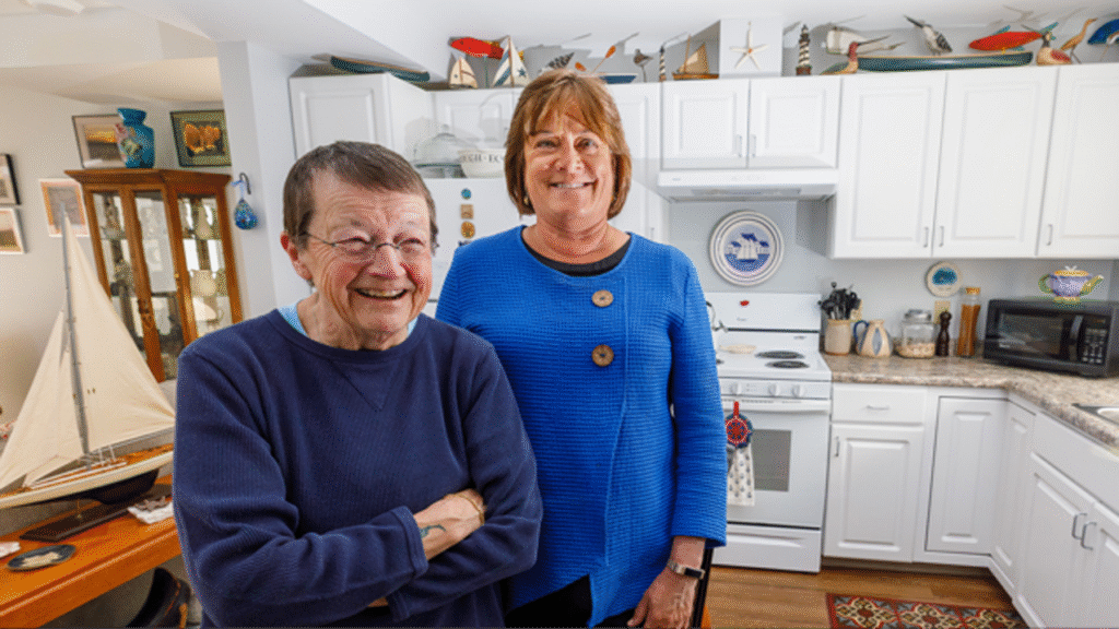 senior female affordable housing resident standing next to female banking professional in the kitchen of her home