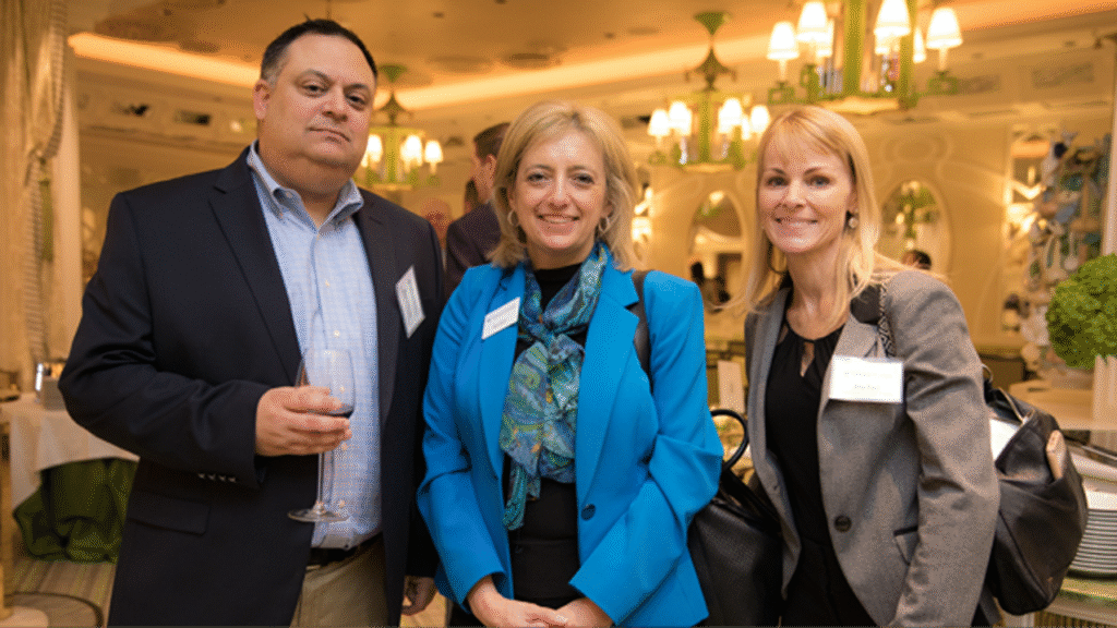 man standing next to two women as all three pose for a photo in a ballroom