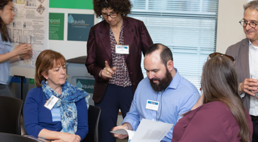 woman standing over seated woman and man who are reviewing documents