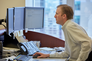Man sitting at desk using mouse while looking at the computer screen in front of him
