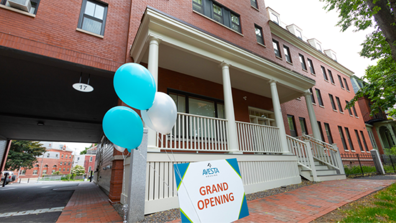 balloons and grand opening sign in front of an affordable housing development