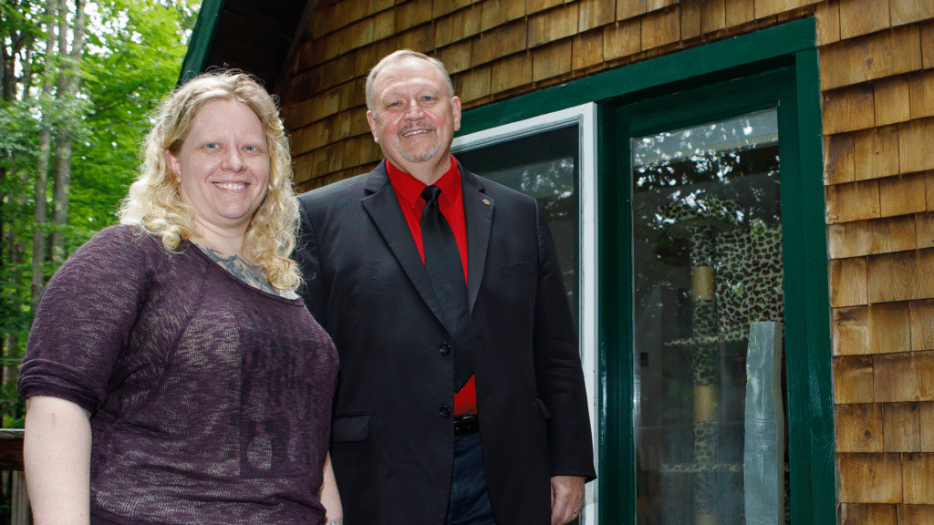 woman and man standing with home in background