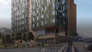 multistory building with cyclist on a paved community path in front of it and pedestrians walking past next to a road with cars driving past