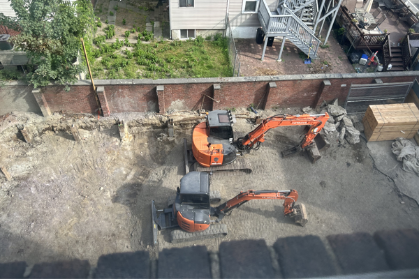 Two pieces of construction equipment in a fenced in area with dirt surrounding the equipment.